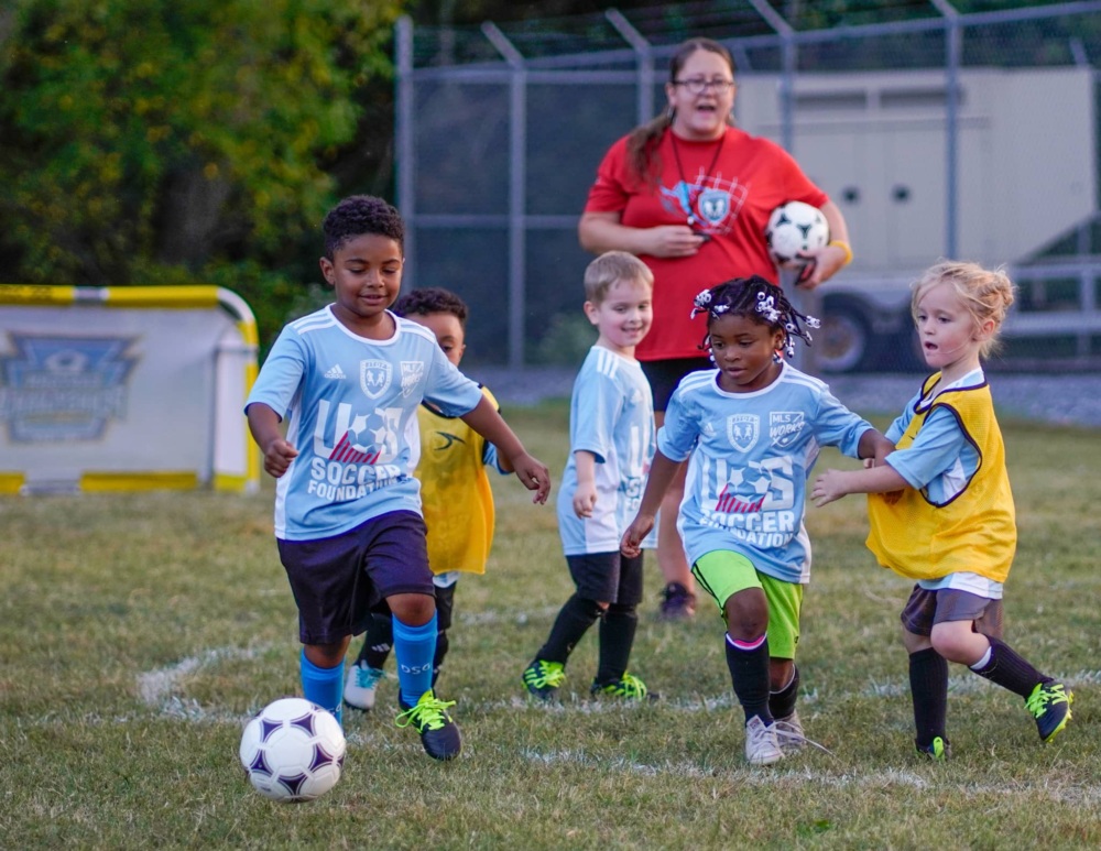 Coach and kids playing soccer